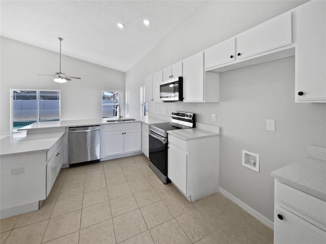 kitchen featuring lofted ceiling, sink, white cabinetry, stainless steel appliances, and kitchen peninsula