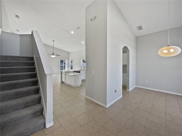 stairway with tile patterned flooring, high vaulted ceiling, and ceiling fan