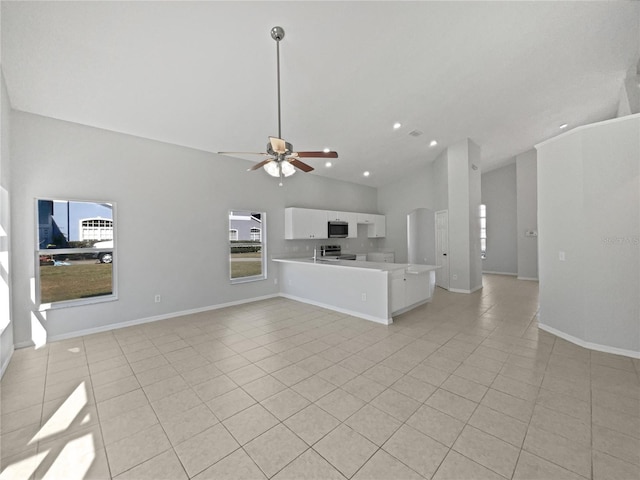 unfurnished living room with ceiling fan, high vaulted ceiling, and light tile patterned floors