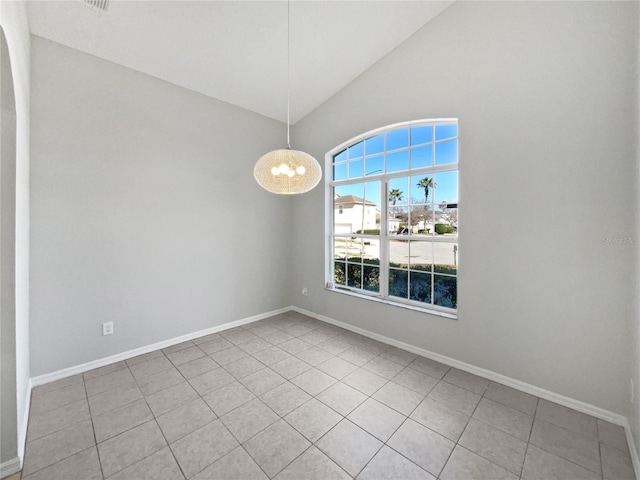 tiled empty room featuring lofted ceiling and a notable chandelier