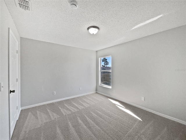 empty room with carpet floors and a textured ceiling