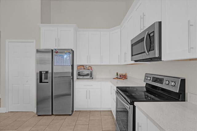 kitchen featuring stainless steel appliances, white cabinetry, light stone countertops, and light tile patterned floors