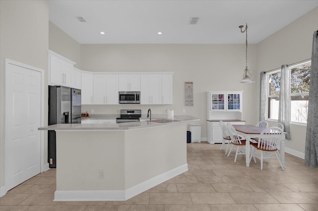 kitchen with white cabinetry, stainless steel appliances, a kitchen island with sink, and pendant lighting