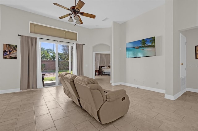 living room with ceiling fan, a high ceiling, and light tile patterned floors