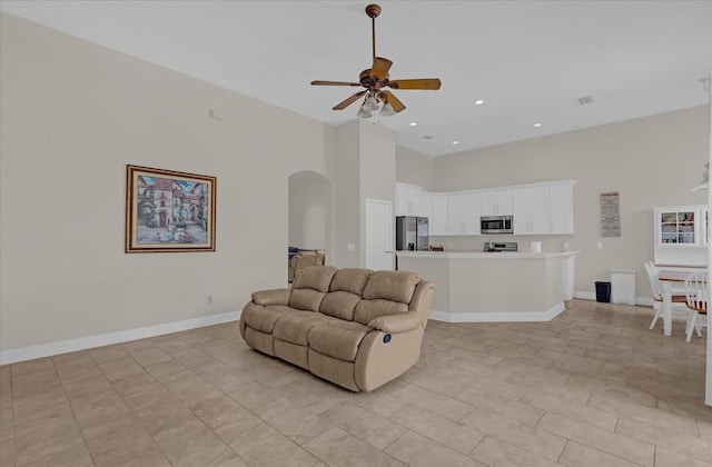 living room with ceiling fan and a high ceiling