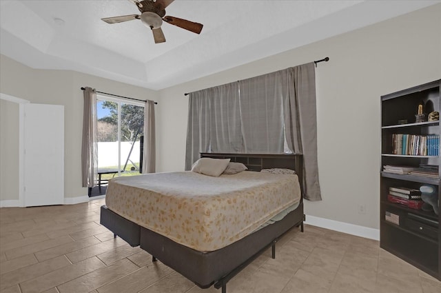 bedroom featuring a raised ceiling, light wood-type flooring, and ceiling fan