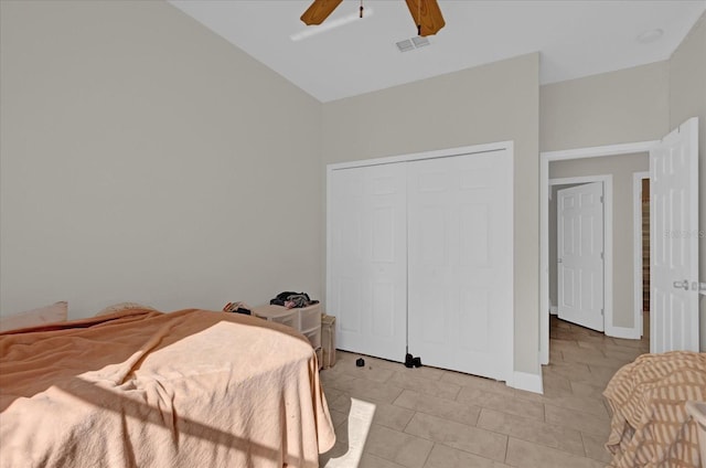 tiled bedroom featuring vaulted ceiling, ceiling fan, and a closet