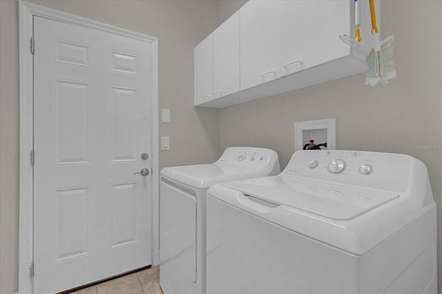 washroom with cabinets, washing machine and dryer, and light tile patterned floors