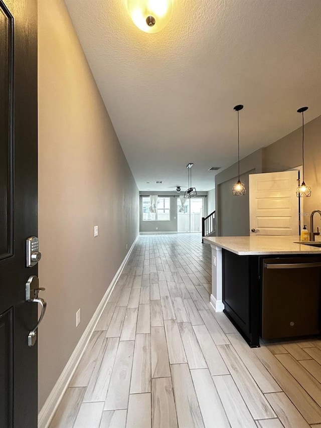 kitchen with decorative light fixtures, dishwasher, sink, and a textured ceiling