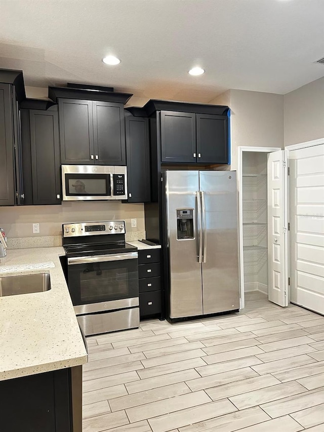 kitchen with appliances with stainless steel finishes, sink, and light stone counters