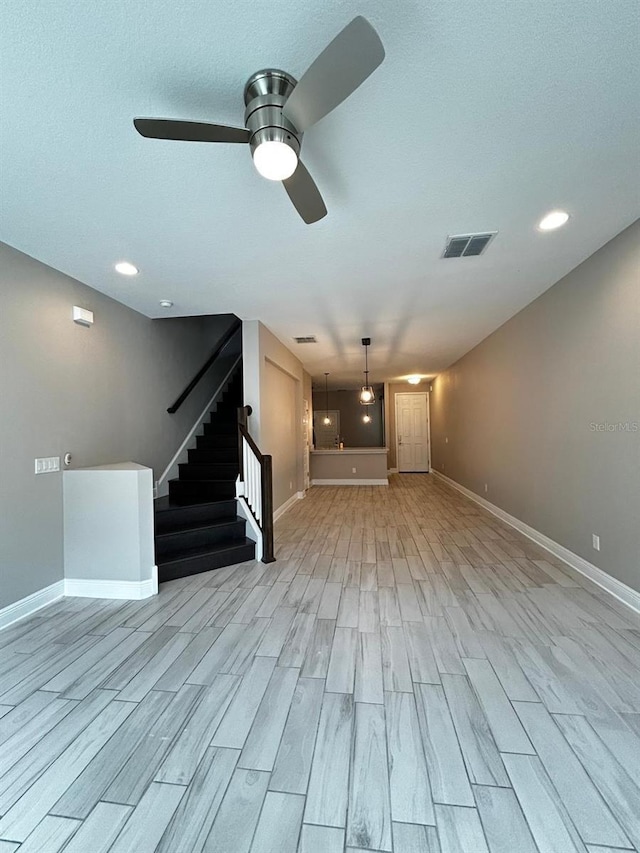 unfurnished living room featuring ceiling fan, a textured ceiling, and light hardwood / wood-style flooring