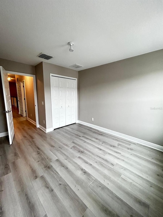 unfurnished bedroom with light hardwood / wood-style floors, a closet, and a textured ceiling