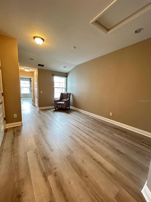 unfurnished room with a textured ceiling and light wood-type flooring