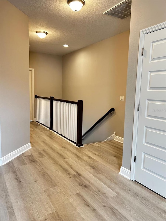 stairs with hardwood / wood-style floors and a textured ceiling