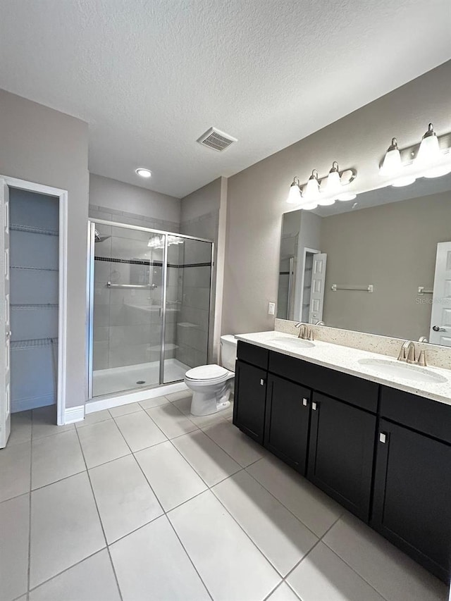 bathroom with vanity, a shower with shower door, tile patterned floors, and a textured ceiling