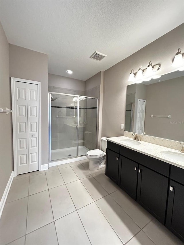 bathroom with tile patterned flooring, vanity, a textured ceiling, toilet, and walk in shower