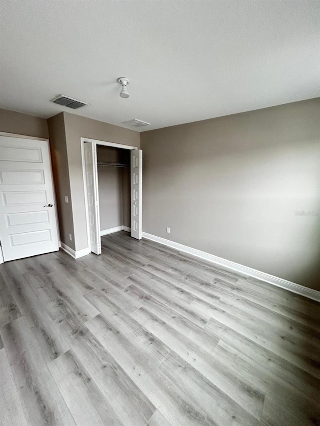 unfurnished bedroom featuring a textured ceiling, light wood-type flooring, and a closet