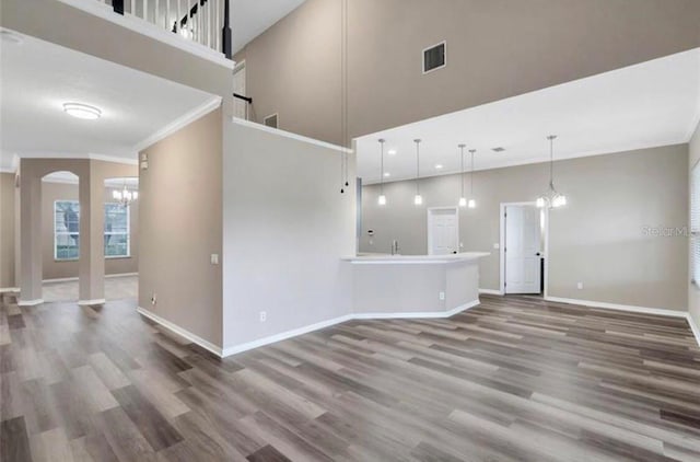 unfurnished living room featuring wood-type flooring, a chandelier, and a high ceiling