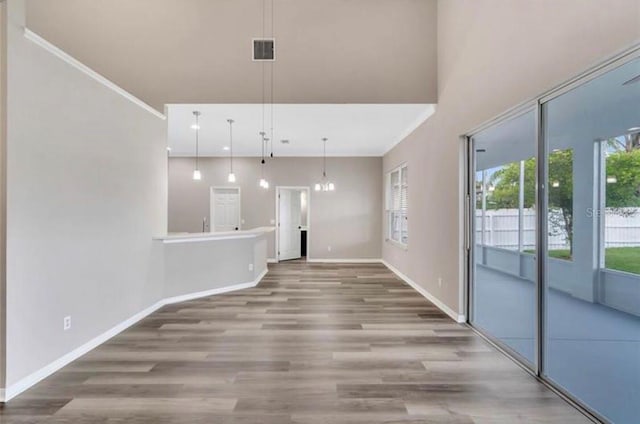 unfurnished living room featuring a towering ceiling and wood-type flooring