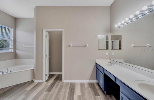 bathroom with a tub to relax in, hardwood / wood-style floors, and vanity