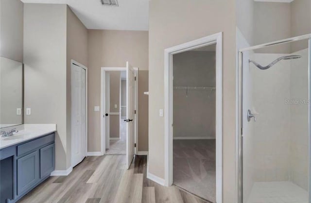 bathroom with a shower with door, vanity, and hardwood / wood-style flooring