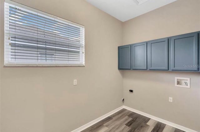 laundry area with electric dryer hookup, hookup for a washing machine, dark hardwood / wood-style floors, and cabinets