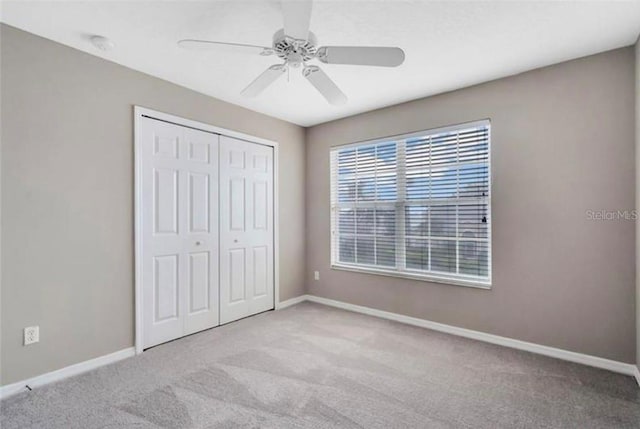 unfurnished bedroom featuring ceiling fan, light colored carpet, and a closet