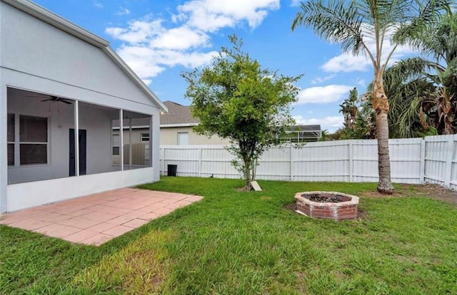 view of yard featuring a sunroom, a patio area, and a fire pit