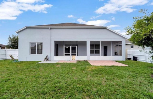 rear view of property featuring a yard, a patio area, and a sunroom