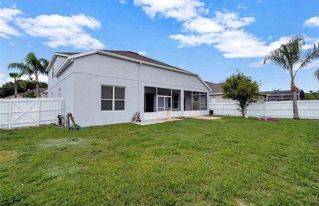 back of house featuring a patio, a sunroom, and a lawn