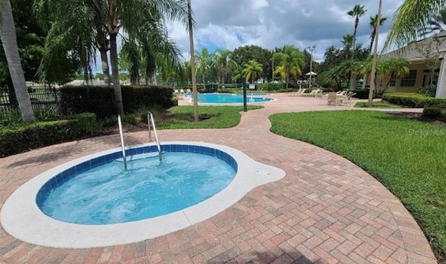 view of pool with a hot tub, a yard, and a patio area