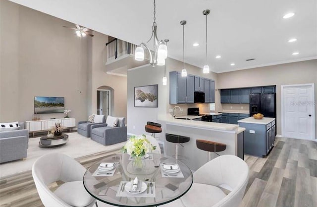 dining room featuring a towering ceiling, light hardwood / wood-style floors, sink, and a notable chandelier