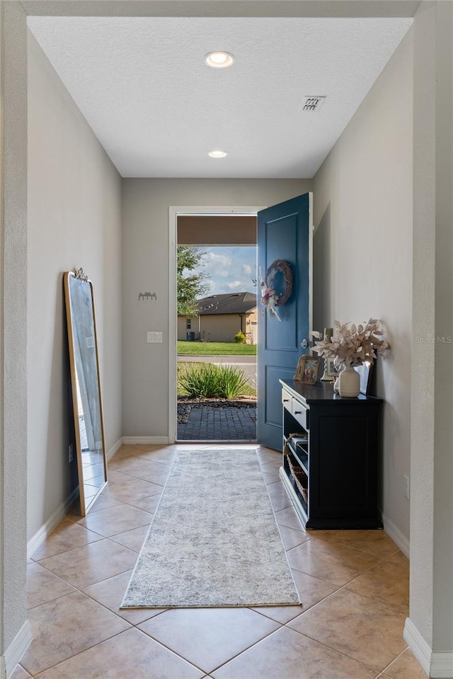 foyer entrance with light tile patterned floors and a textured ceiling