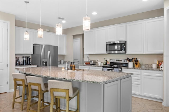 kitchen with white cabinetry, hanging light fixtures, stainless steel appliances, and a center island with sink