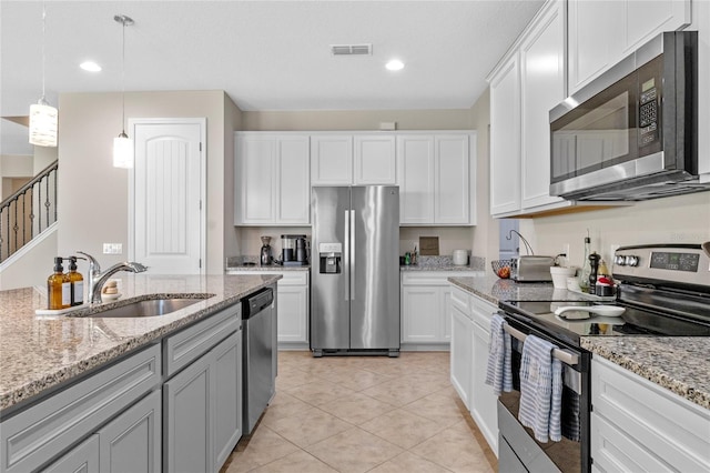 kitchen with sink, white cabinetry, light stone counters, hanging light fixtures, and stainless steel appliances