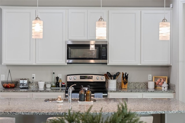 kitchen with pendant lighting, stainless steel appliances, light stone countertops, and white cabinets