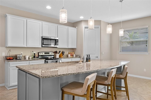 kitchen with stainless steel appliances, white cabinetry, and a kitchen island with sink