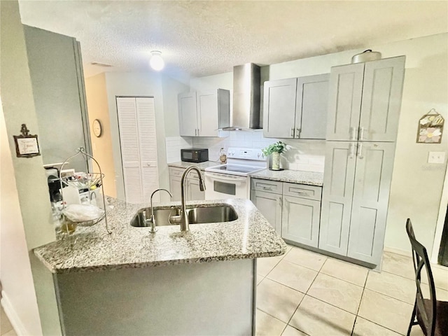 kitchen featuring electric range, light stone countertops, sink, and wall chimney range hood