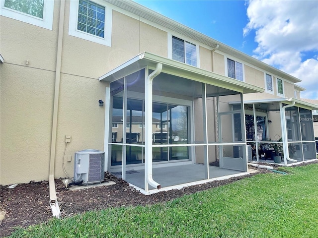 rear view of house featuring cooling unit, a sunroom, a patio area, and a lawn