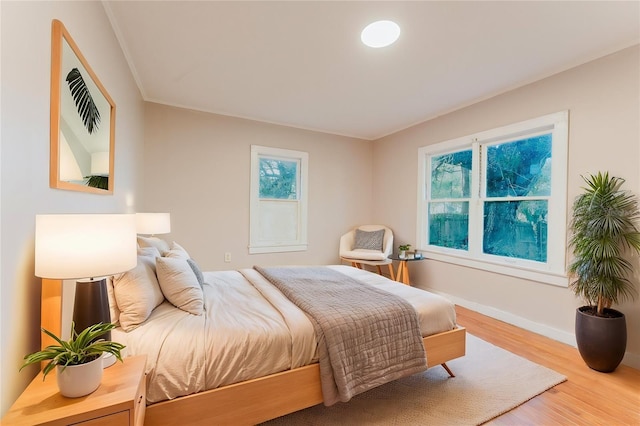 bedroom featuring baseboards, wood finished floors, and ornamental molding