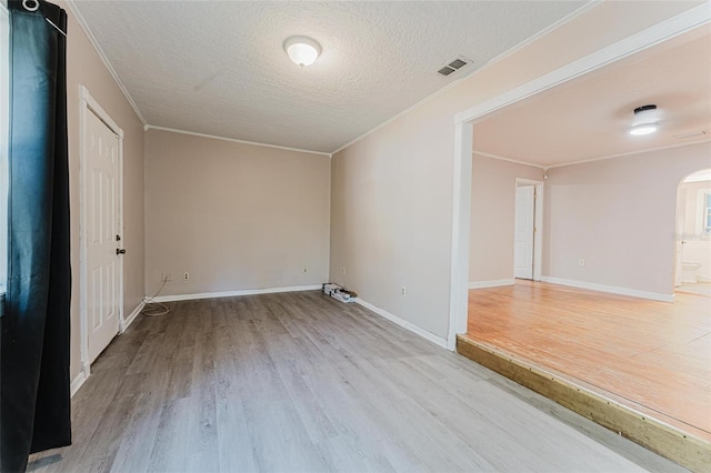 spare room with visible vents, crown molding, wood finished floors, arched walkways, and a textured ceiling