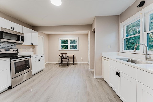 kitchen featuring light wood finished floors, a healthy amount of sunlight, appliances with stainless steel finishes, and a sink