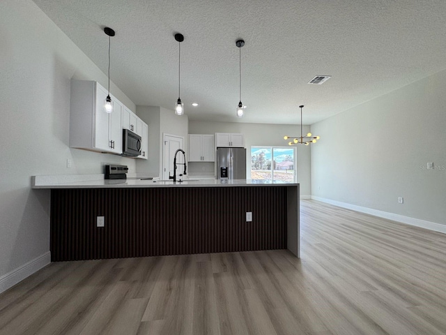 kitchen featuring light wood-type flooring, stainless steel appliances, white cabinets, sink, and kitchen peninsula