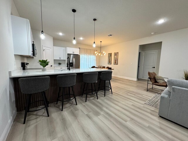 150 Marion Oaks Trl, Ocala, FL 34473 - kitchen with light countertops, a kitchen breakfast bar, a peninsula, stainless steel appliances, and light wood-style flooring