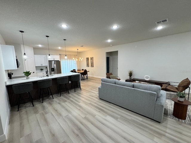 150 Marion Oaks Trl, Ocala, FL 34473 - living area featuring visible vents, baseboards, a chandelier, a textured ceiling, and light wood-style flooring