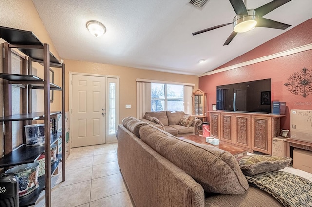 tiled living room featuring ceiling fan, vaulted ceiling, and a textured ceiling