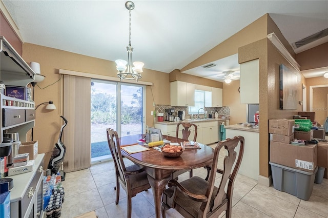 tiled dining space featuring vaulted ceiling, ceiling fan with notable chandelier, sink, and a wealth of natural light