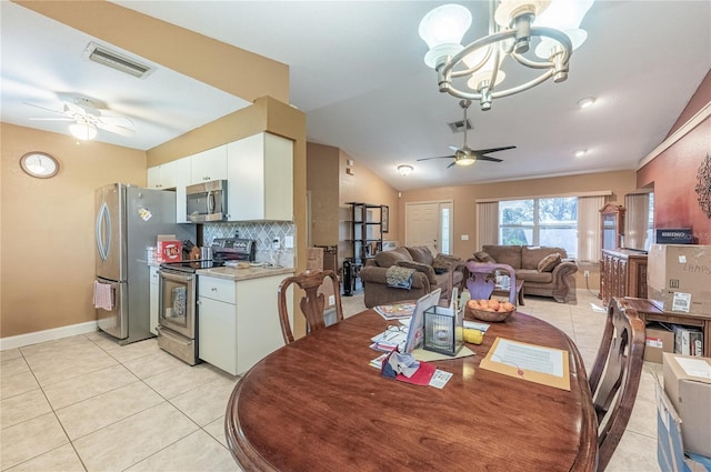 tiled dining area with lofted ceiling and ceiling fan with notable chandelier