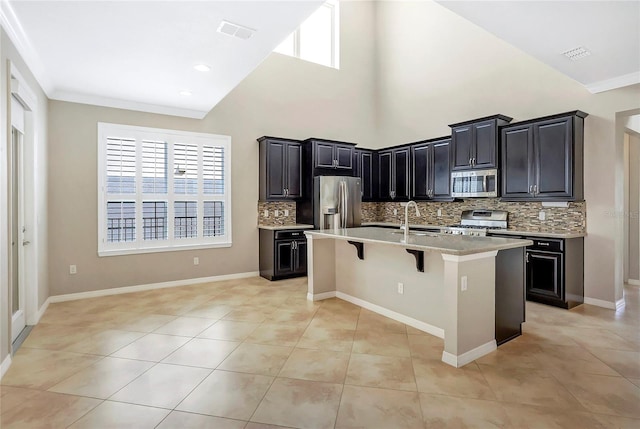 kitchen with sink, light tile patterned floors, a kitchen breakfast bar, stainless steel appliances, and an island with sink