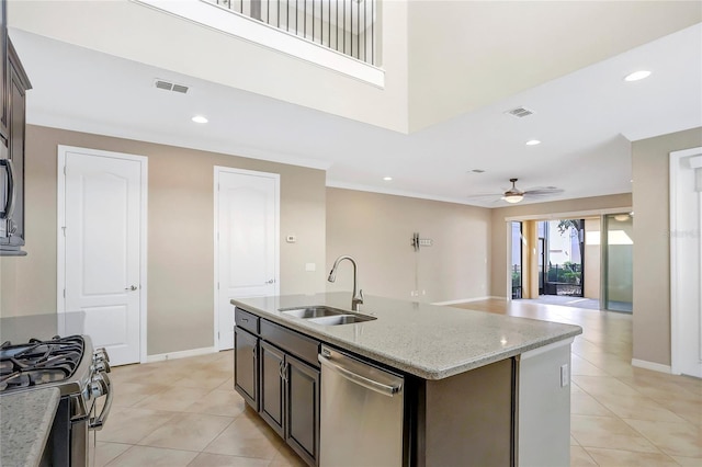 kitchen featuring an island with sink, sink, light tile patterned floors, stainless steel appliances, and light stone countertops